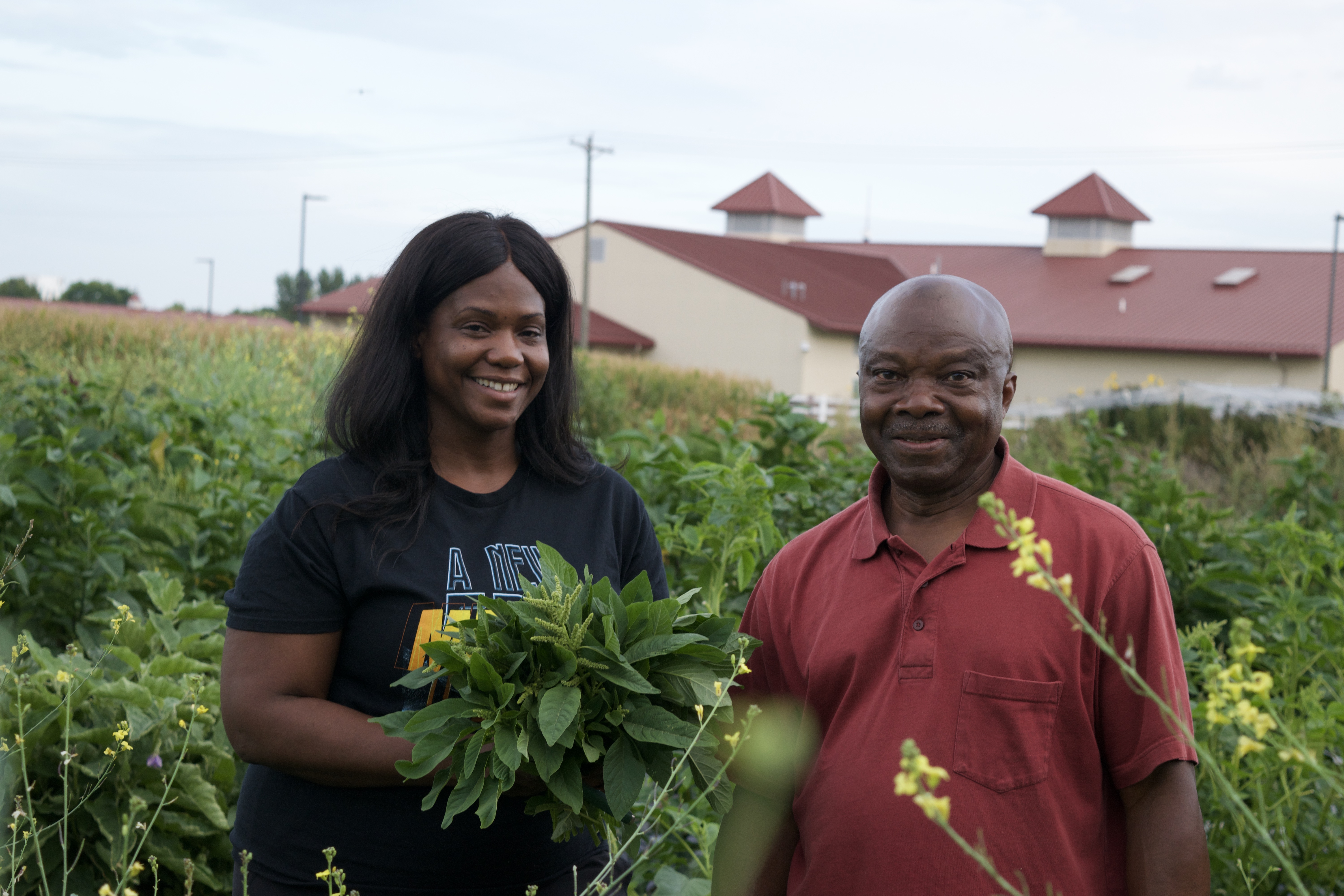 People smiling in field with bundles of greens